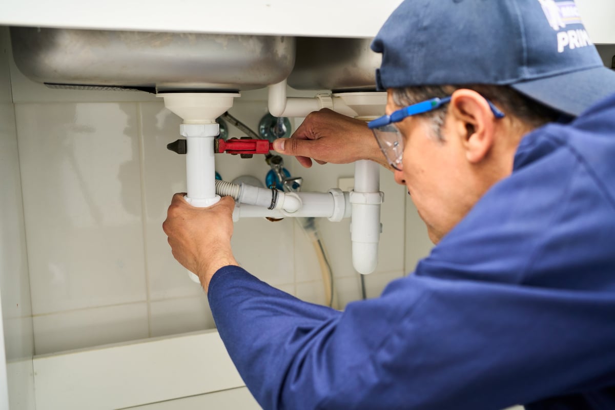Plomero colocando una conexión de caño y revisando el sistema de agua